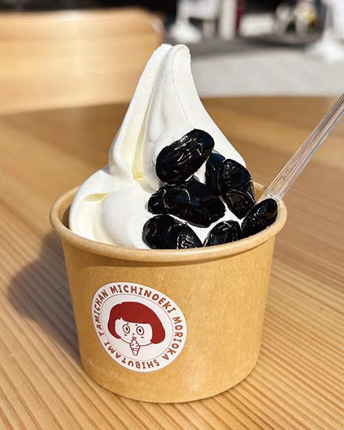 大粒の黒豆がトッピングされたカップ入りの「雁喰豆ソフト」