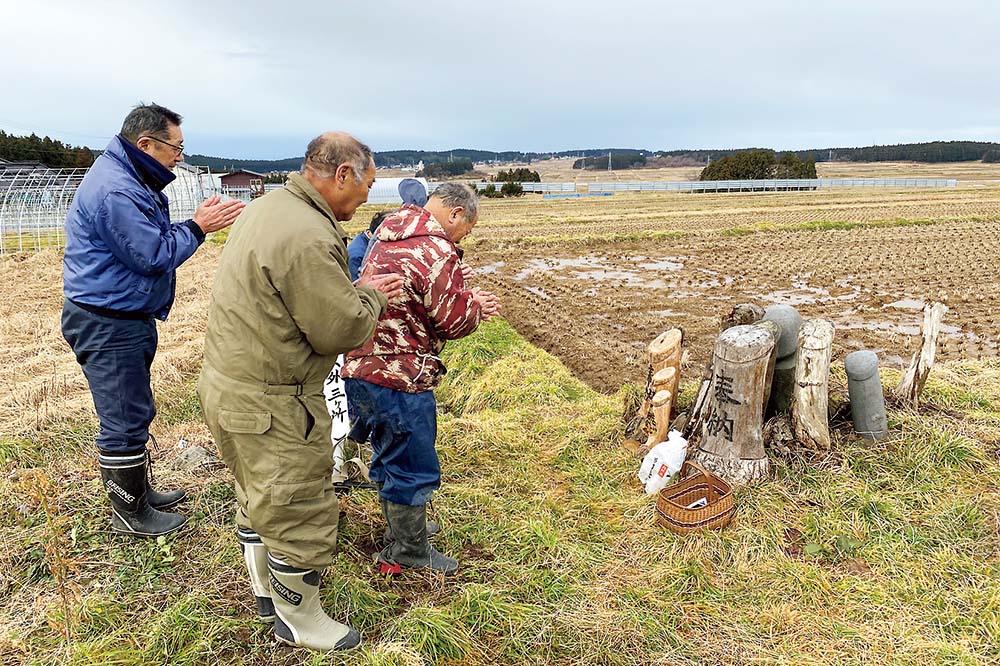 田んぼのなかにあるサエノカミと参拝する人たち